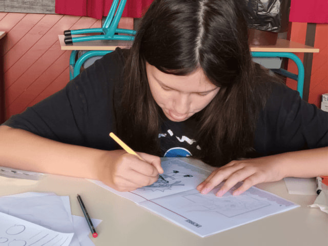 Jeune fille qui s'exerce au dessin Manga lors de sa colo de vacances Manga cet automne