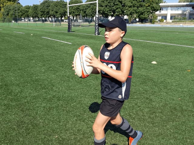 Jeune garçon qui s'apprête à faire une passe lors d'un match de rugby en colonie de vacances cet automne