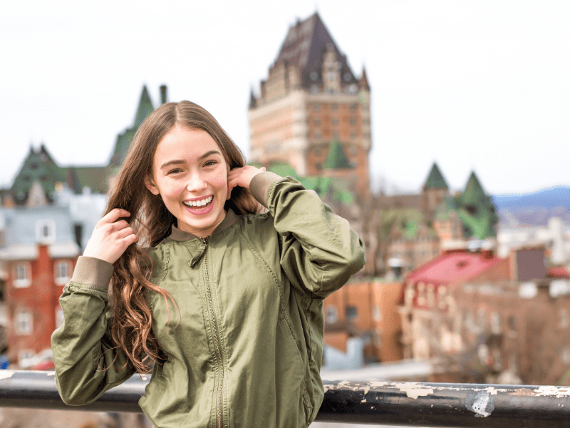 Jeune fille en colo de vacances au Canada qui pose devant le château Frontenac 