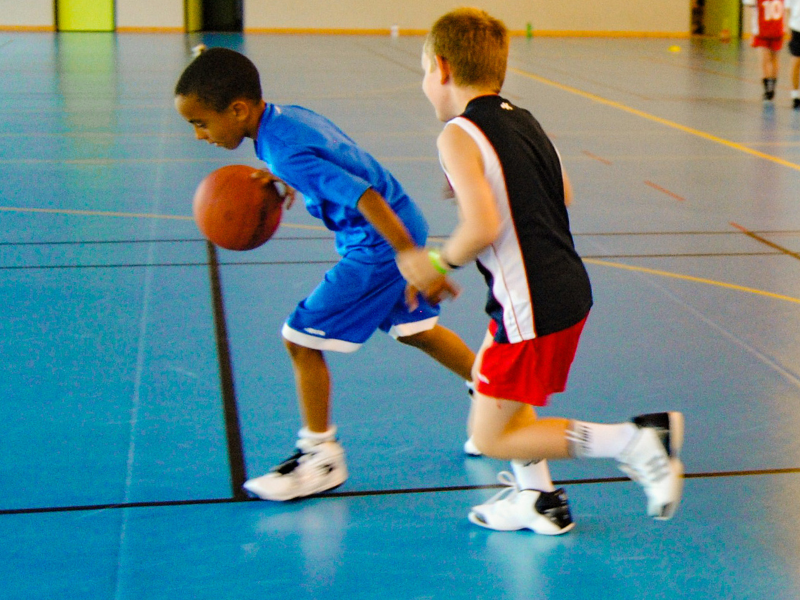 Jeunes garçons qui jouent au basket durant leur colonie multi activités du printemps