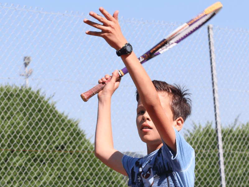 Enfant qui joue au tennis durant sa colonie de vacances multi activités du printemps