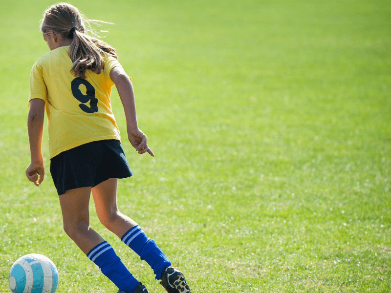 Jeune fille qui pratique le football en colonie de vacances durant ses vacances d'automne