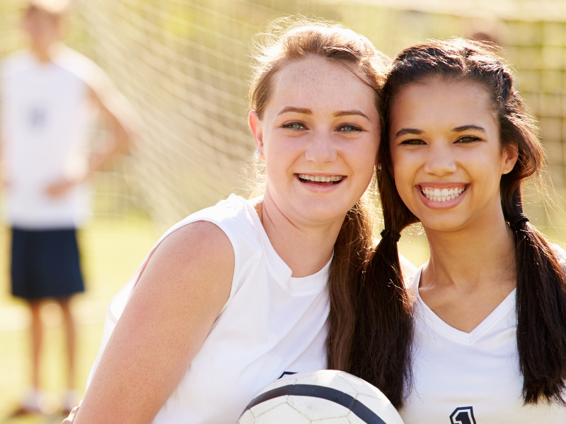 Deux jeunes filles qui sourient et profitent de leur colonie de vacances Football ce printemps