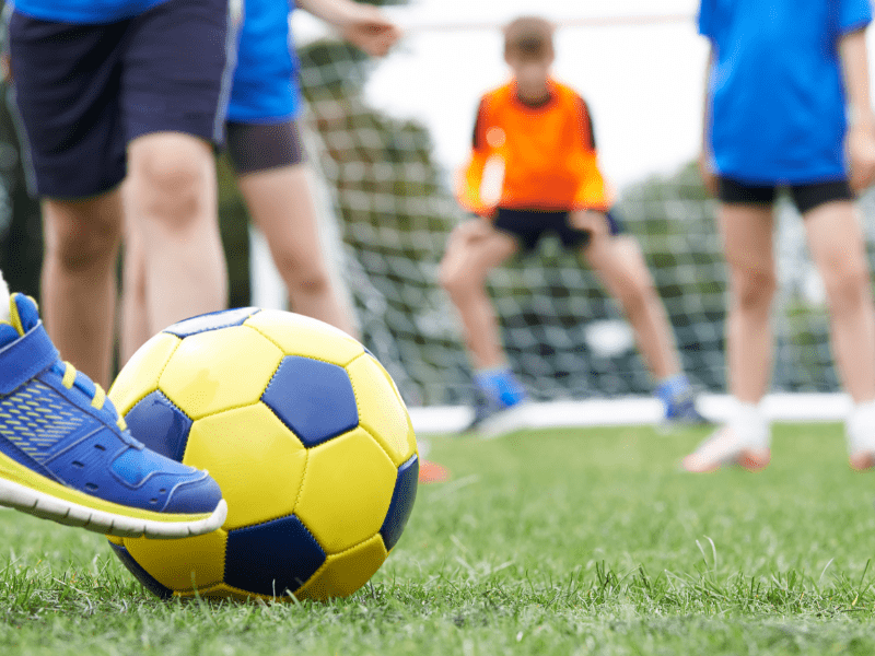 Enfants qui s'entrainent à jouer au foot en colonie de vacances ce printemps