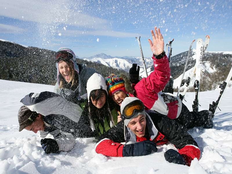 Groupe d'ados qui s'amuse dans la neige en colo de vacances cet hiver