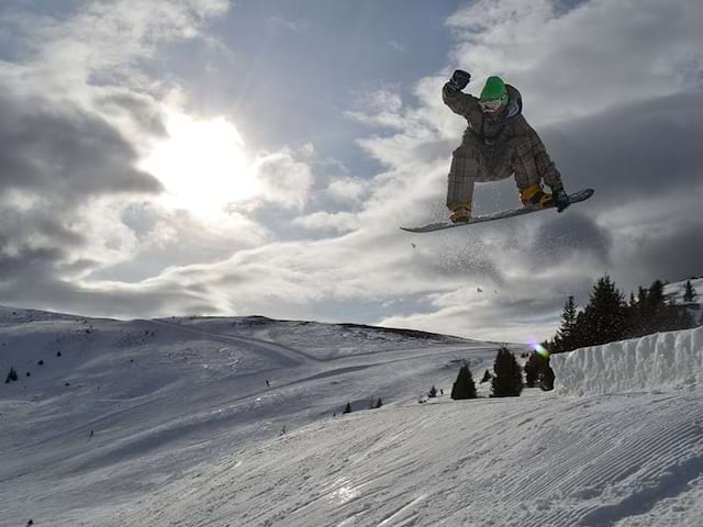 Saut d'un jeune en snow lors d'une colonie de vacances dans les Dolomites