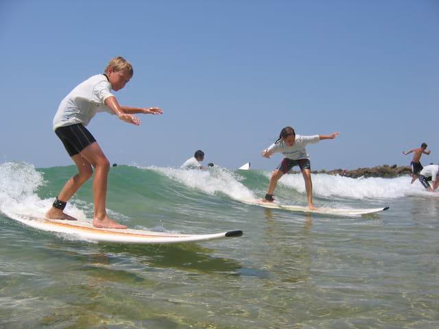 Enfant apprenant à faire du surf en colonie de vacances cet été