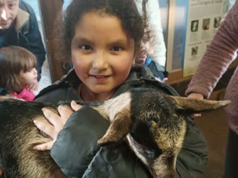 Jeune fille qui porte une chèvre lors d'une colo de vacances Yapa'ski au Nid d'Alpin