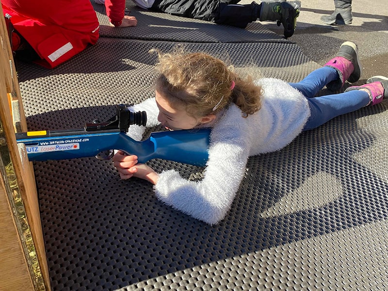 Une enfant s'exerce au tir à la carabine lors d'une colo de vacances au Nid d'Alpin