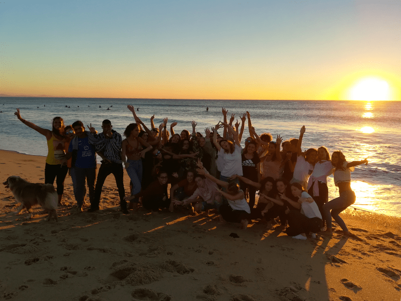 Groupe d'ados en colo de vacances Surf Camp qui posent devant le coucher de soleil