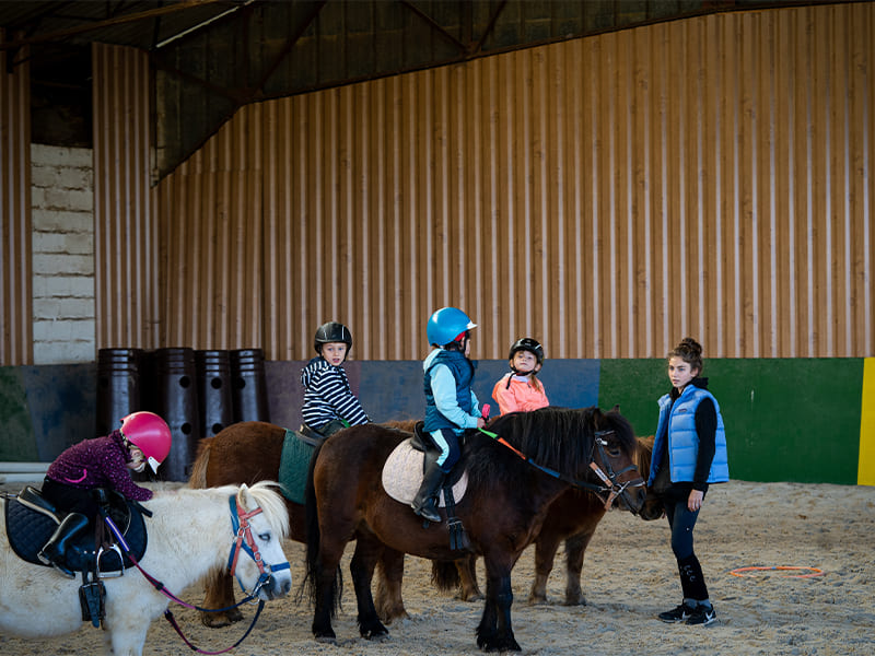 Manège et enfants sur leurs chevaux lors d'une colo de vacances équestre