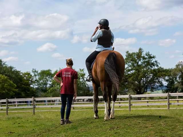 Moniteur et élève sur son cheval lors d'une colo de vacances équestre cet été