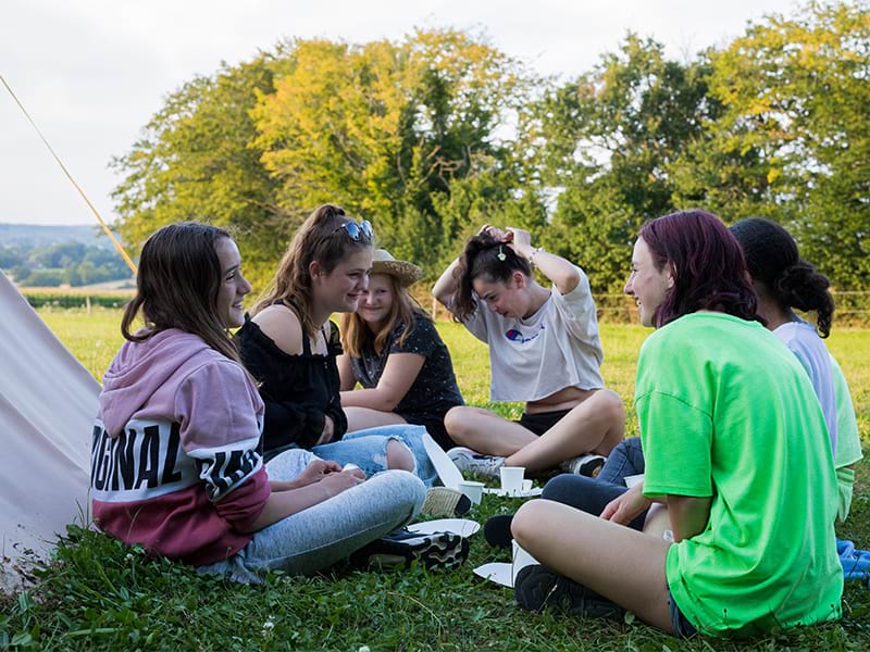 Vue sur des jeunes filles qui rient durant leur colo de vacances dédiée à l'équitation