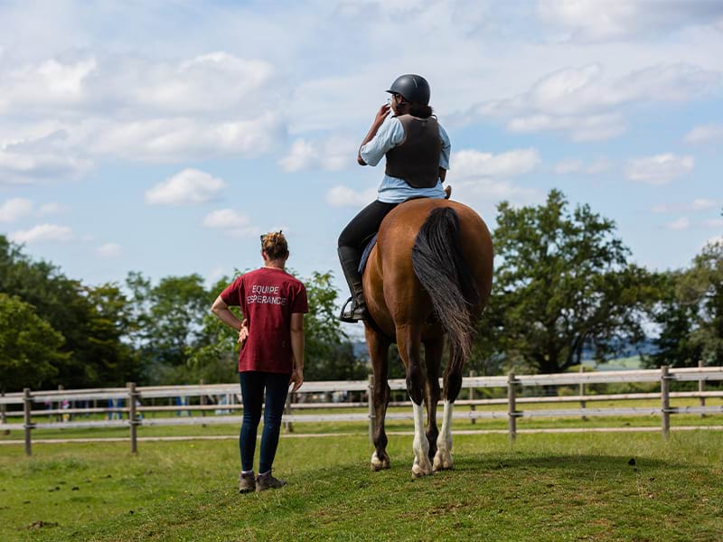 Moniteur et élève sur son cheval lors d'une colo de vacances équestre au printemps