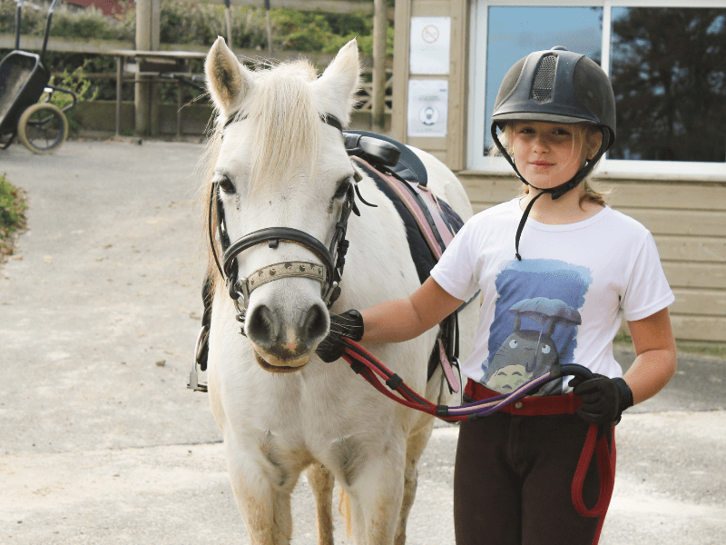 Enfant qui s'amuse durant sa colonie de vacances spéciale Equitation à la Toussaint