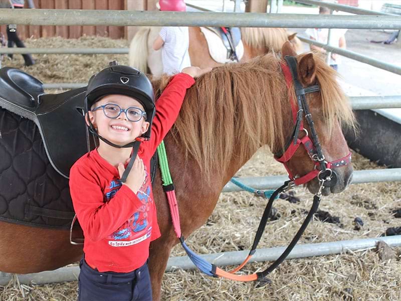 Enfant avec le sourire qui profite de sa colo Equitation durant l'automne