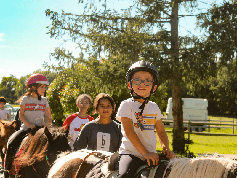 Petit garçon qui fait de l'équitation en colo de vacances au domaine de l'Esperance
