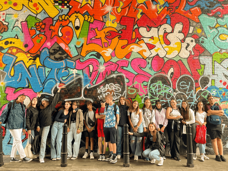 Jeunes ados qui posent devant un graffiti observé en colonie de vacances au printemps 