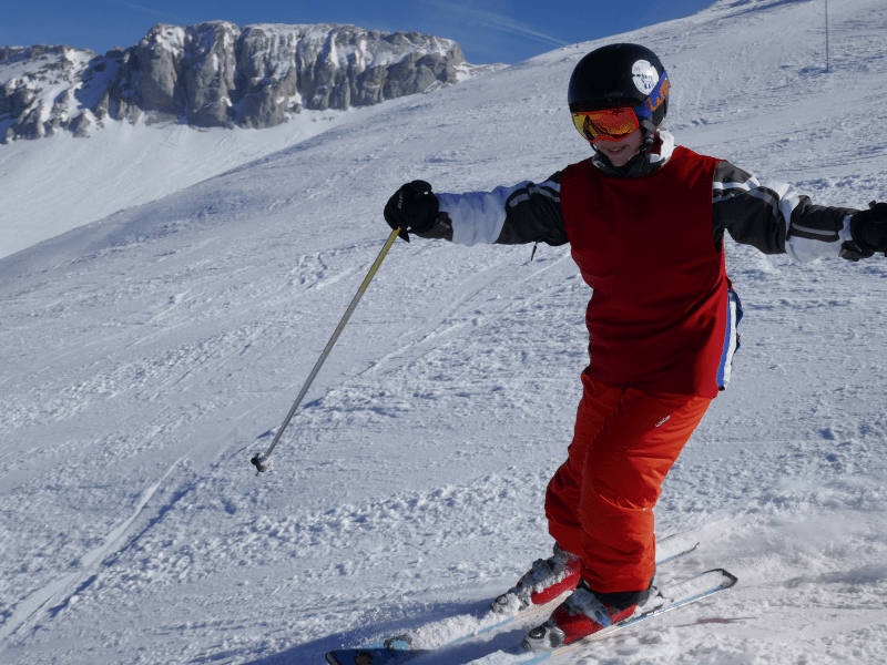 Enfant qui dévale les pistes de ski en colo de vacances cet hiver