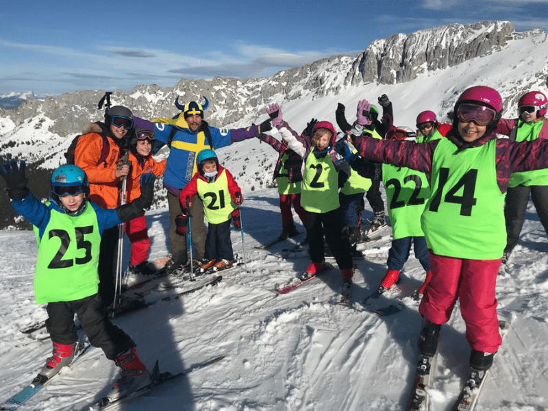 Enfants heureux, qui lèvent les bras en l'air, durant leur colo de vacances Ski cet hiver