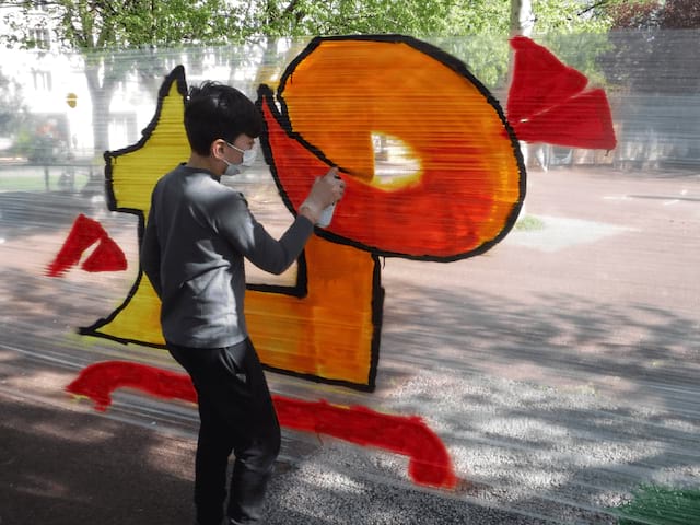 Enfant qui tag des murs durant l'activité graff en colo 