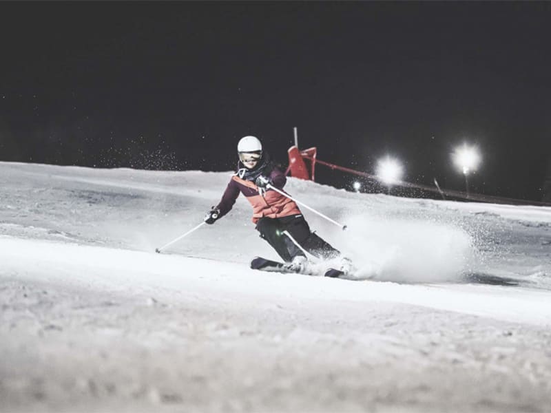 Vue sur la jeune qui descend une piste en ski lors d'une session ski de nuit
